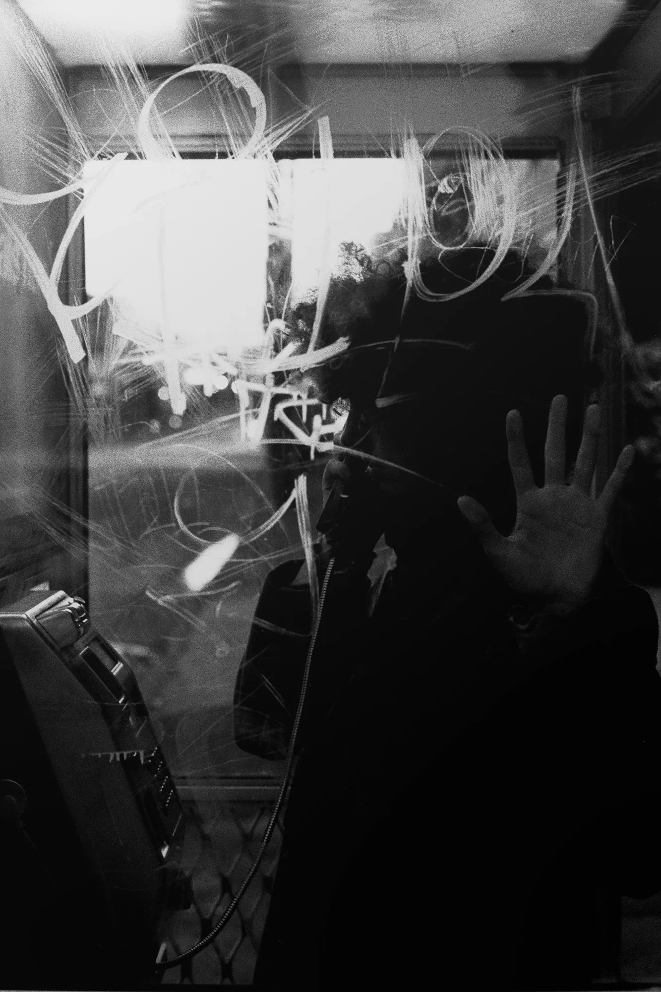 Scratched glass of a phone booth at night, black-and-white film